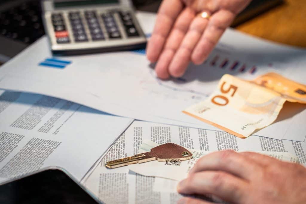 Schlüsselübergabe nach Hausverkauf mit Bargeld und Unterlagen auf dem Tisch